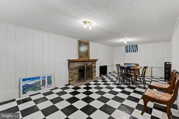 a living room with a black white checkered floor with couches chair and fireplace