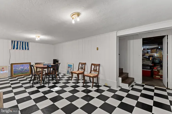 a room with a black white checkered floor with a gaming machine and dining chairs