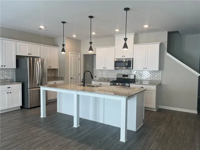 a kitchen with kitchen island granite countertop a sink a counter and stainless steel appliances
