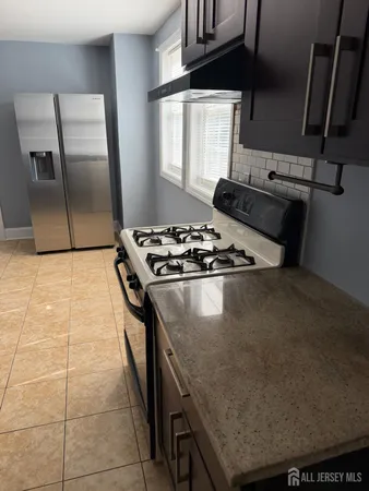 a kitchen with granite countertop a stove a sink a refrigerator and window