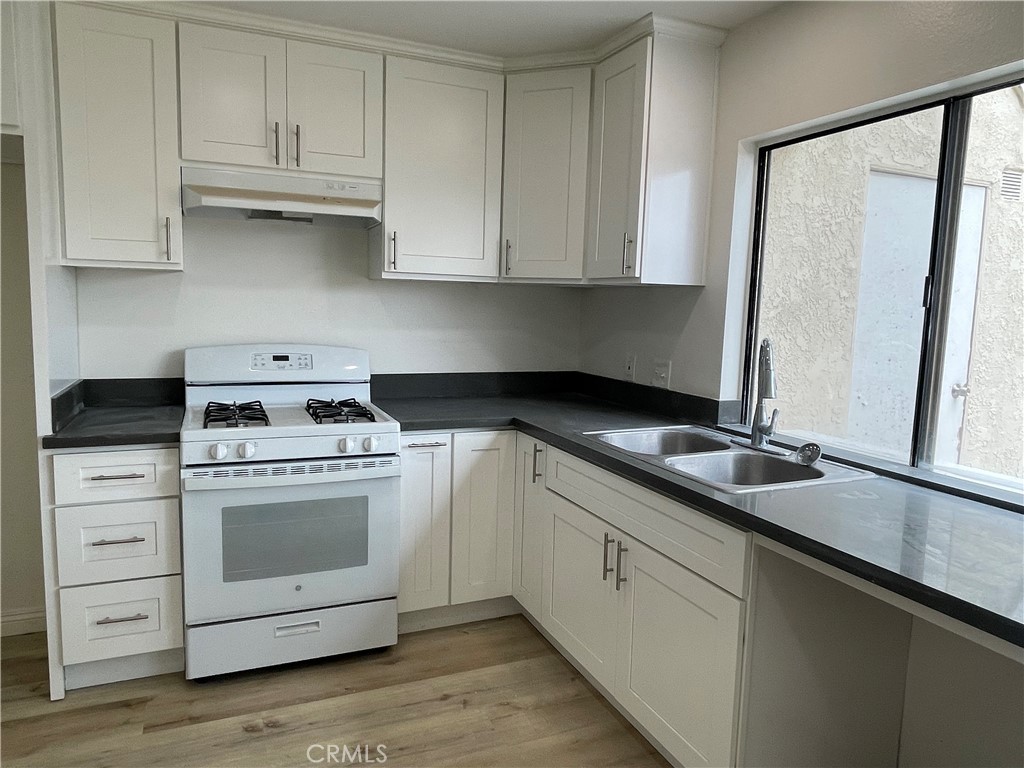 16 Gatewood Irvine, CA 92604 - Photo 6 of 12 a kitchen with granite countertop white cabinets and white appliances