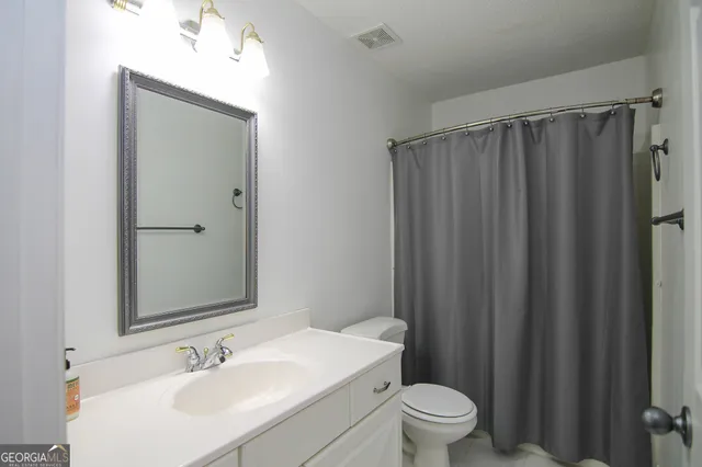 a bathroom with a sink a toilet a mirror and shower curtain