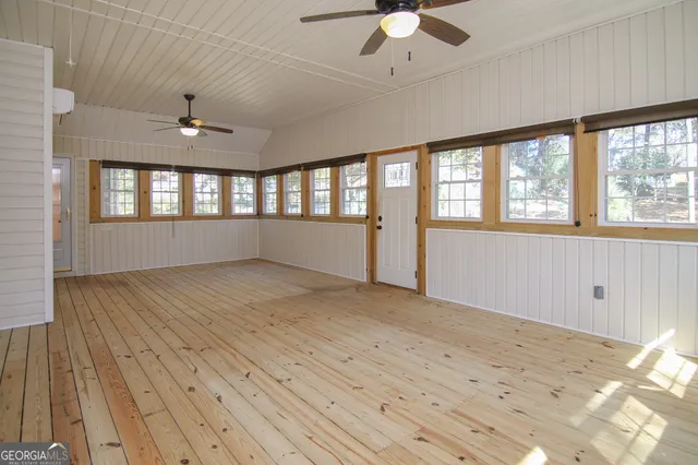 a view of empty room with wooden floor and fan