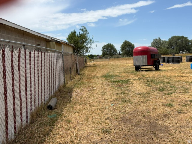 Fort Lane Layton, UT 84041 - Photo 4 of 4 Expansive parcel featuring a chain-link fence with privacy slats, open field space, and distant mature trees