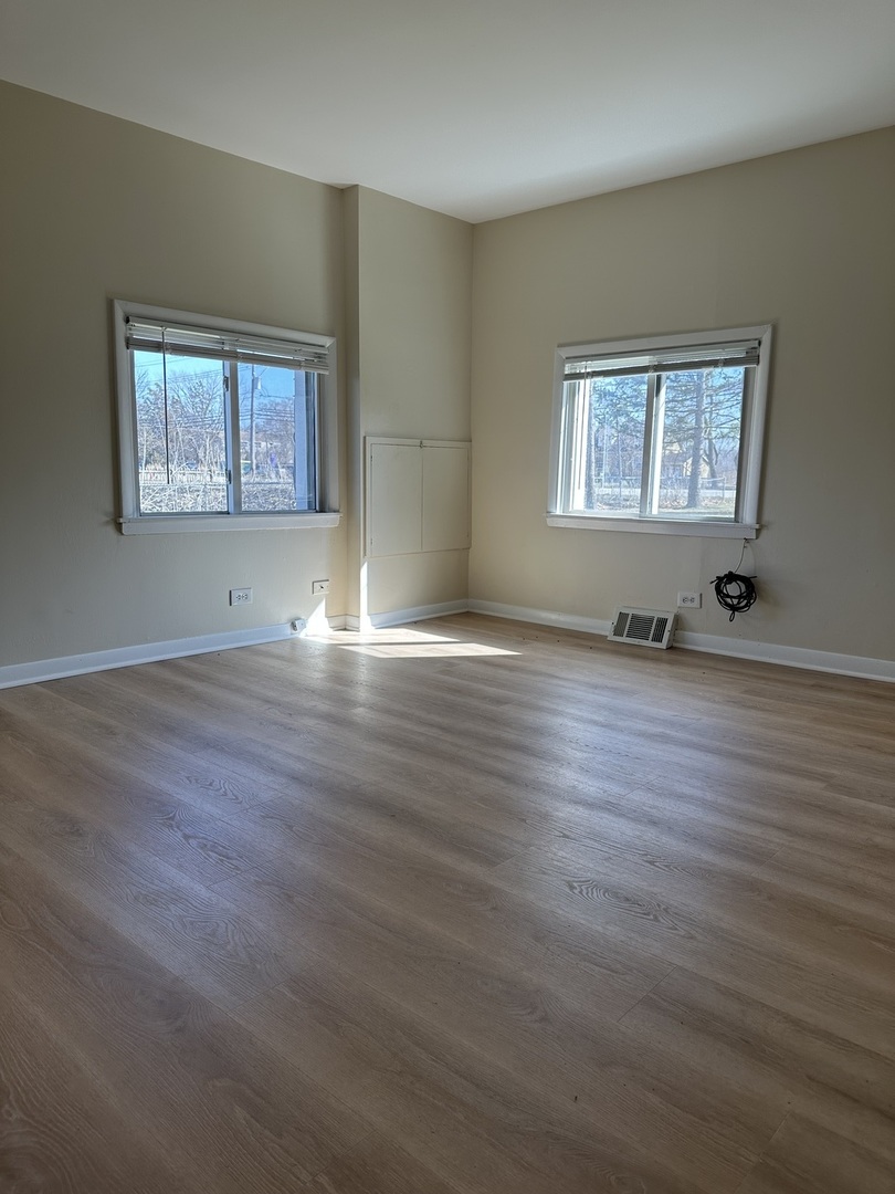 16664 West Aptakisic Road, Unit 1E Lincolnshire, IL 60069 - Photo 5 of 9 a view of an empty room with wooden floor and a window