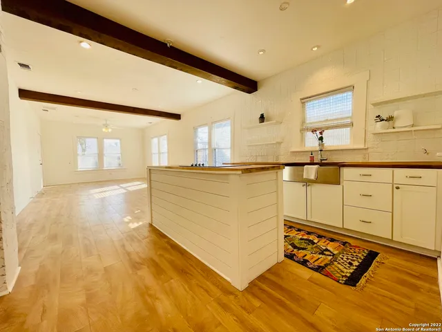 a view of a kitchen with kitchen island a sink wooden floor and counter top space