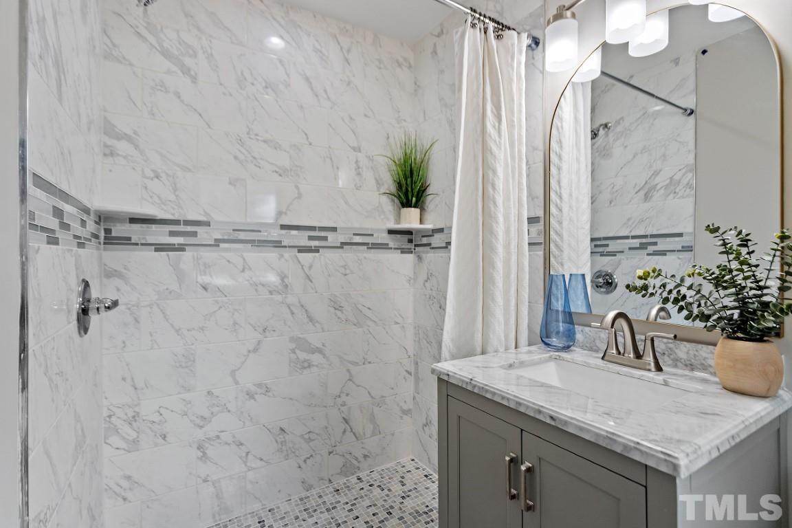 4116 Kilcullen Drive Raleigh, NC 27604 - Photo 15 of 28 a bathroom with a granite countertop sink a mirror and shower