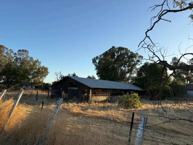 a view of a wooden house with a bench next to a yard