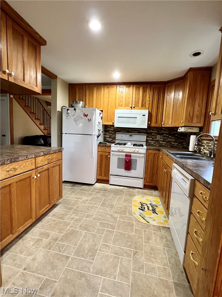Kitchen with white appliances, light tile floors, tasteful backsplash, and sink
