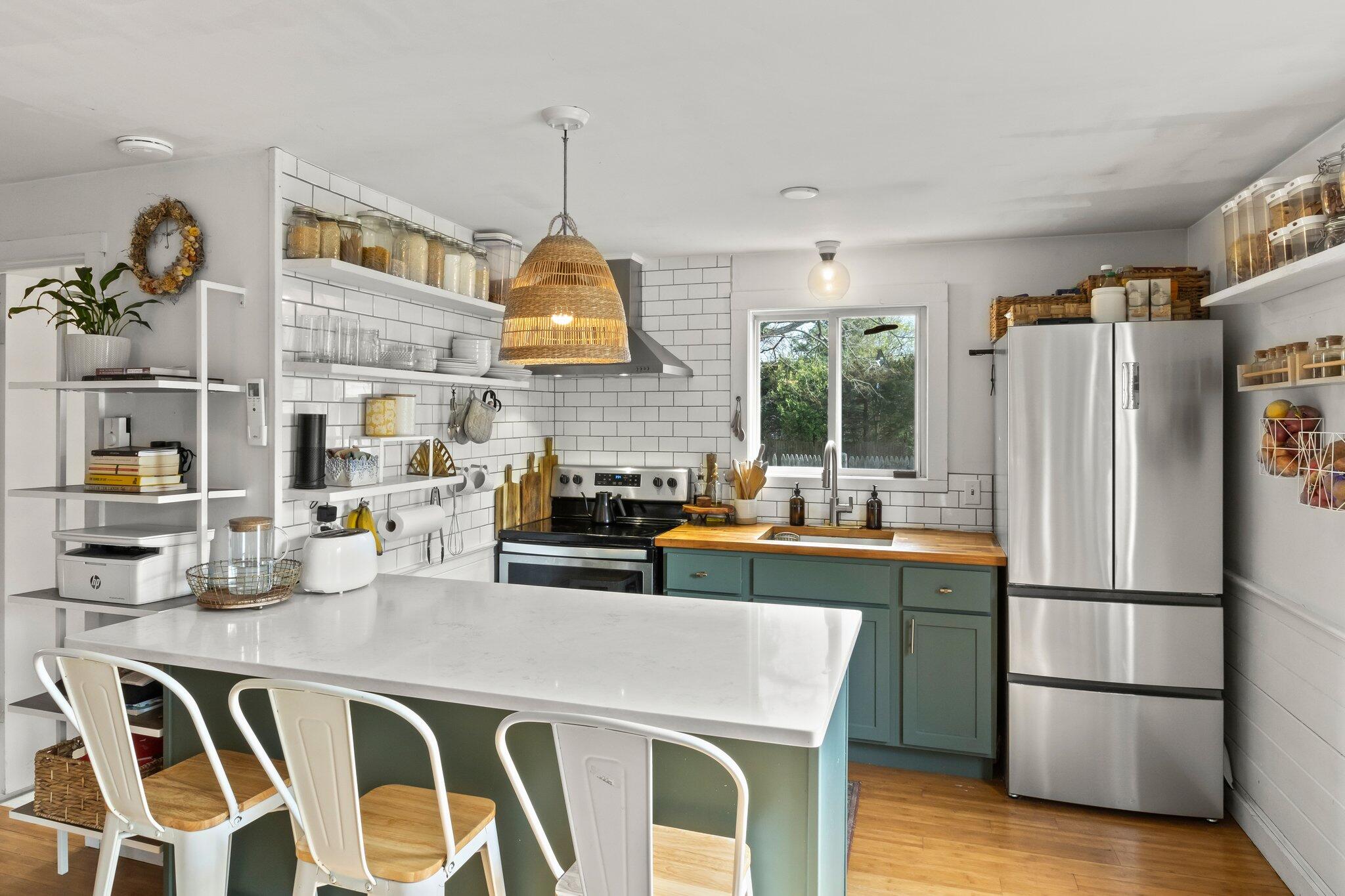 582 Massasoit Road Eastham, MA 02642 - Photo 9 of 45 a kitchen with stainless steel appliances granite countertop a refrigerator a sink dishwasher a dining table and chairs with wooden floor