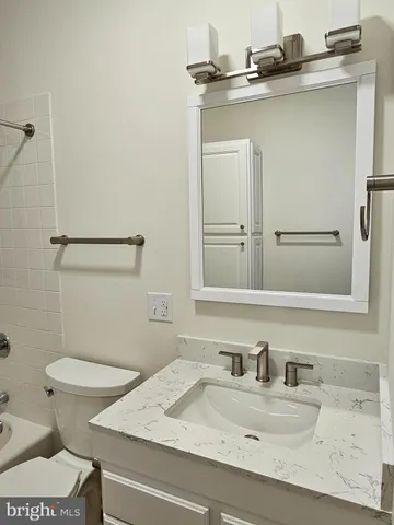 a bathroom with a granite countertop sink a toilet and a mirror