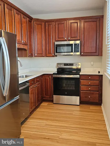 a kitchen with stainless steel appliances granite countertop a stove top oven a refrigerator and dishwasher with wooden floor