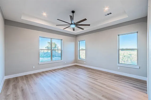 a view of an empty room with a window and wooden floor