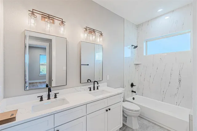 a bathroom with a toilet a sink a mirror a bathtub and shower