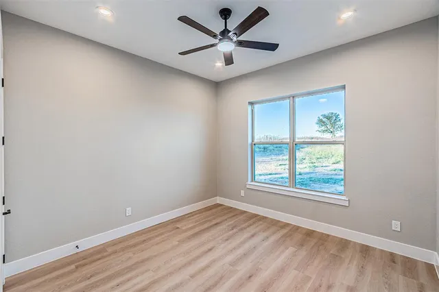 an empty room with a window and a ceiling fan