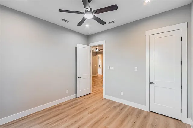 an empty room with wooden floor a ceiling fan and staircase