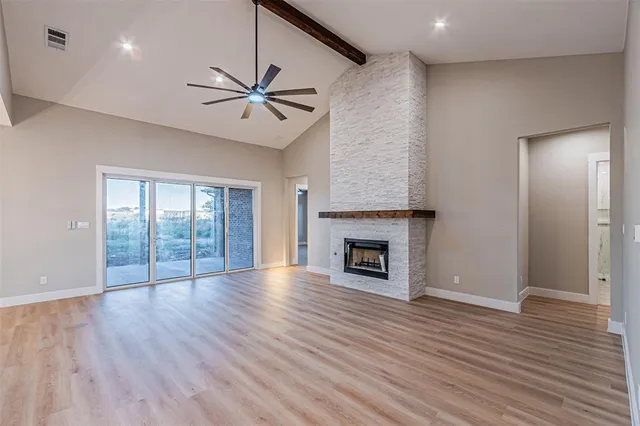an empty room with wooden floor a ceiling fan and windows