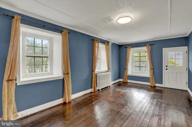 an empty room with wooden floor fan and windows