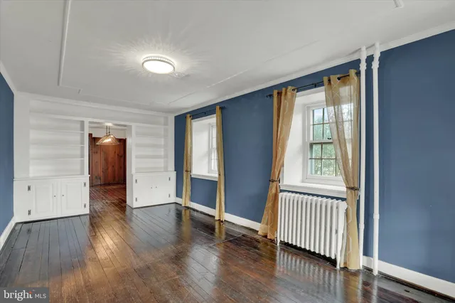 an empty room with wooden floor cabinet and windows
