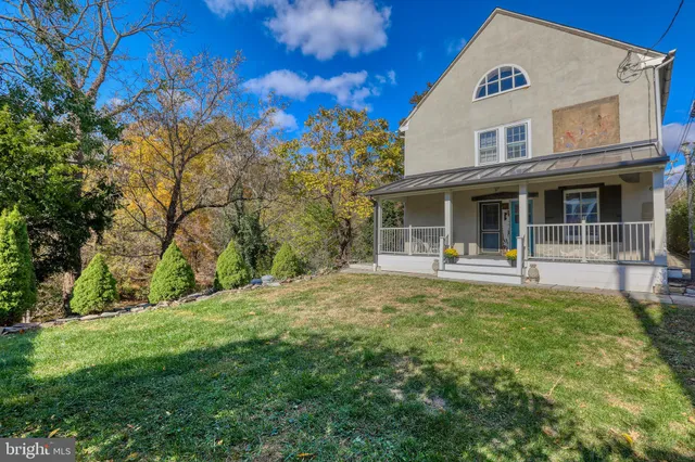 a backyard of a house with table and chairs under an umbrella