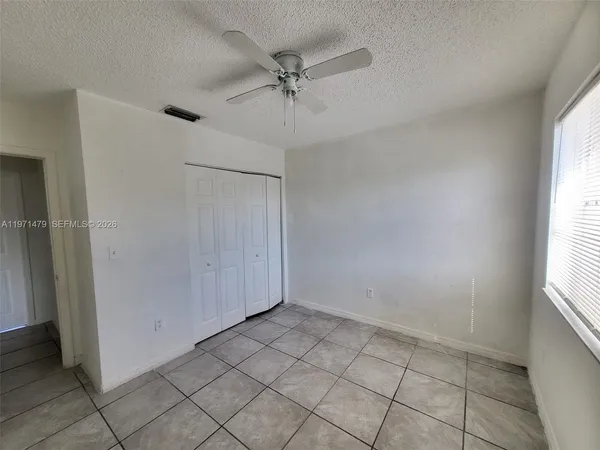 an empty room with a ceiling fan and window