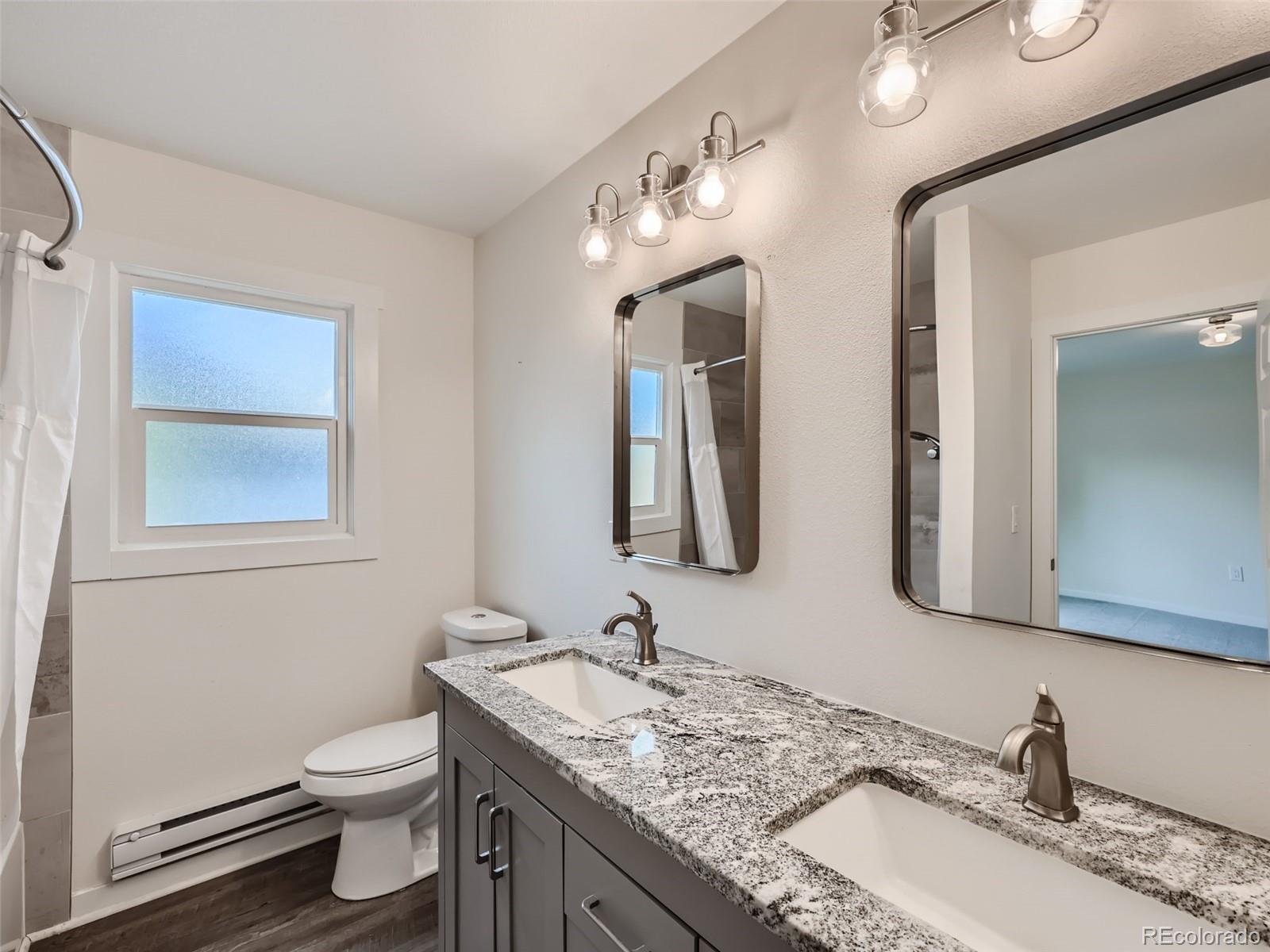 6124 Powell Road Parker, CO 80134 - Photo 22 of 50 a bathroom with a granite countertop sink vanity mirror and toilet