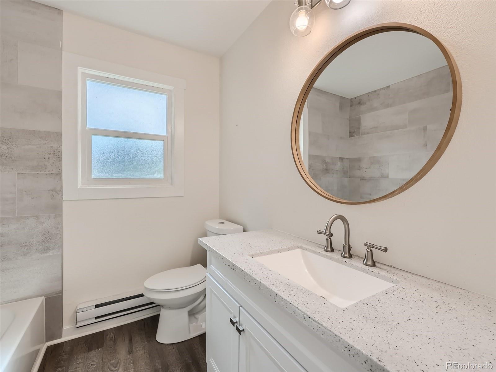6124 Powell Road Parker, CO 80134 - Photo 27 of 50 a bathroom with a granite countertop toilet a sink and a mirror