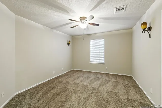 an empty room with windows and fan