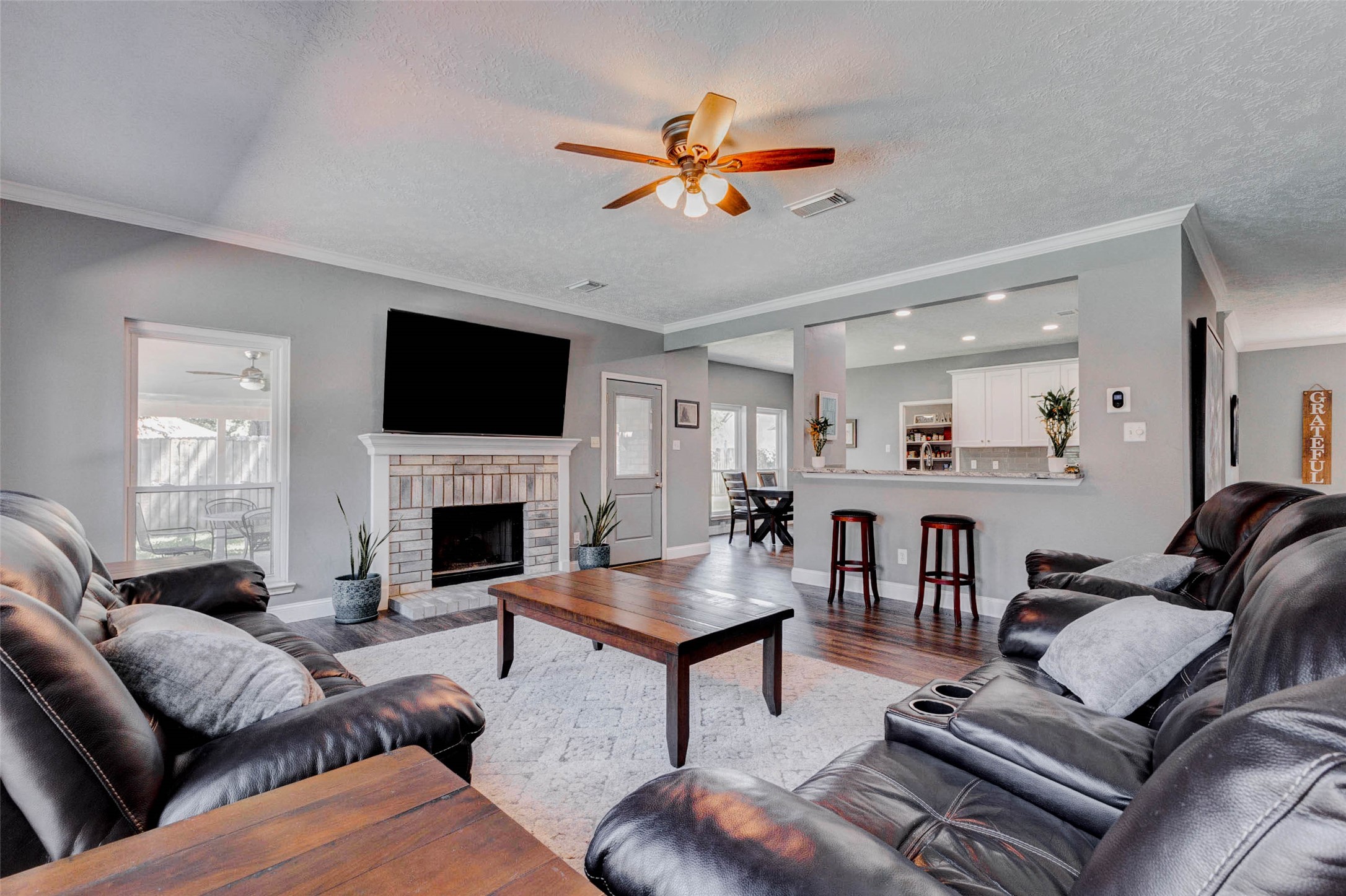9215 Landry Boulevard Spring, TX 77379 - Photo 19 of 42 Wood look flooring and a ceiling fan complete this spacious and inviting gathering space. The generous layout offers plenty of space for a large sectional or your favorite loveseat and sofa combination, making it easy to create a comfortable and functional seating arrangement.