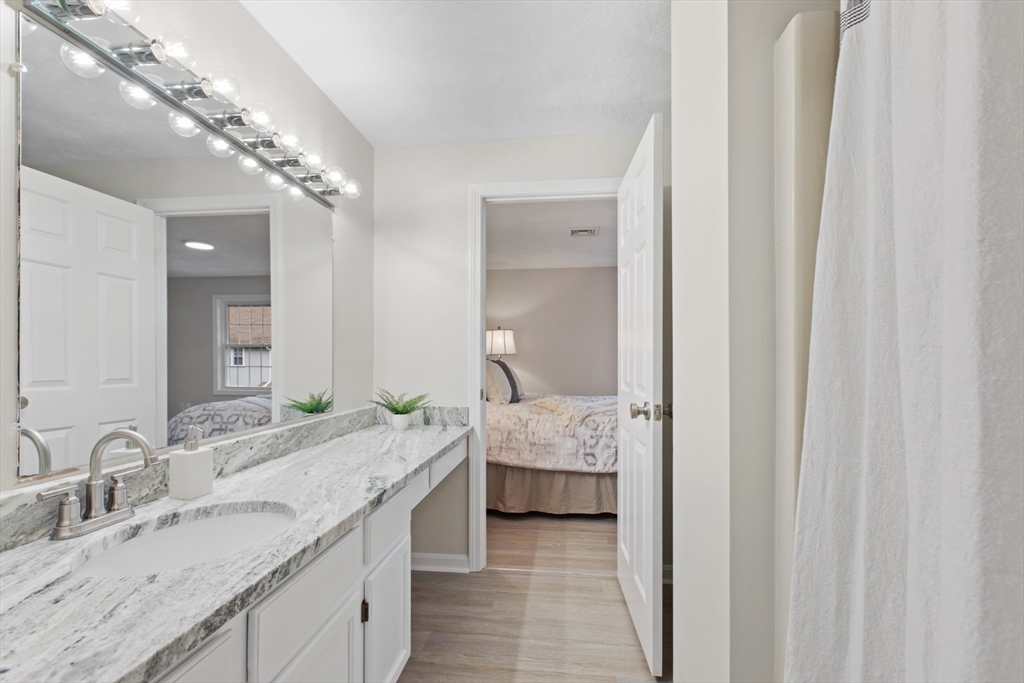 79 Patrick Road, Unit 79 Tewksbury, MA 01876 - Photo 13 of 18 a en suite bathroom with a granite countertop sink and a mirror