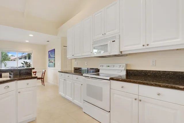 a kitchen with granite countertop white cabinets and white appliances