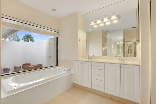 a spacious bathroom with a granite countertop sink a mirror and a bathtub with shower