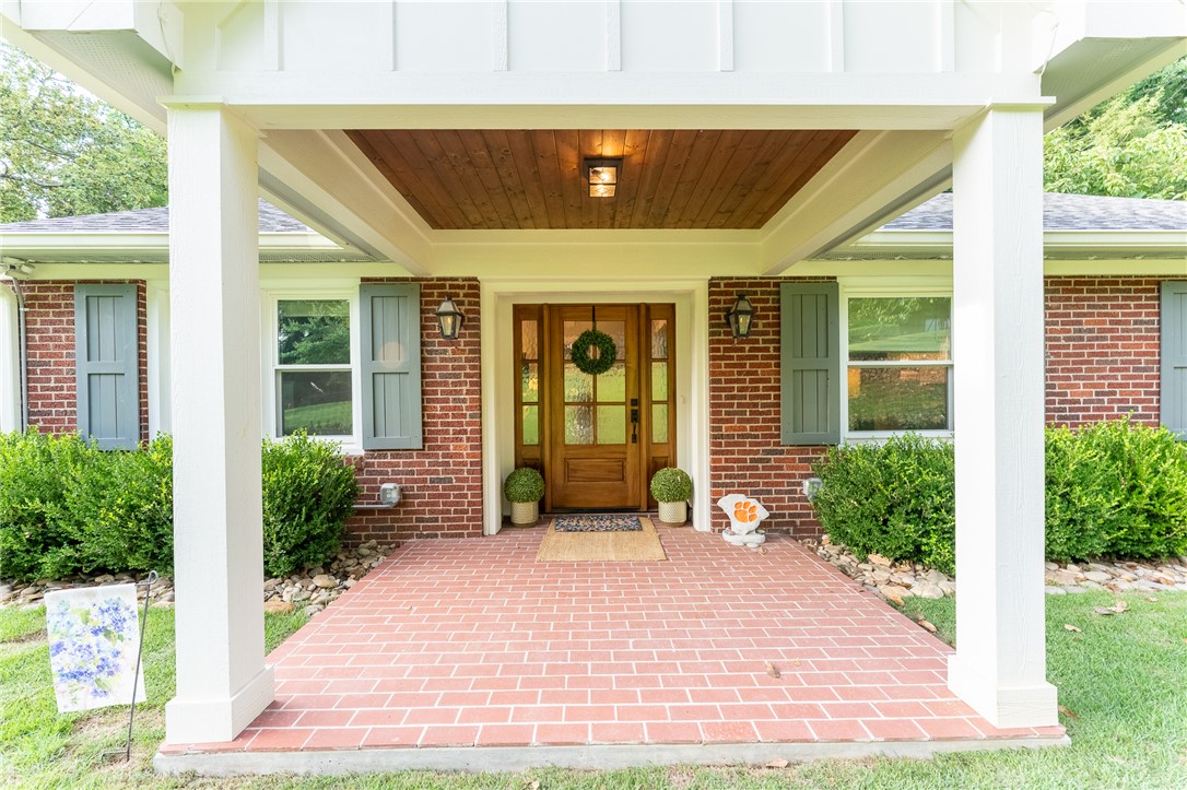 103 Riggs Drive Clemson, SC 29631 - Photo 2 of 50 A welcoming front porch features a wood ceiling, brick flooring, and fresh landscaping.