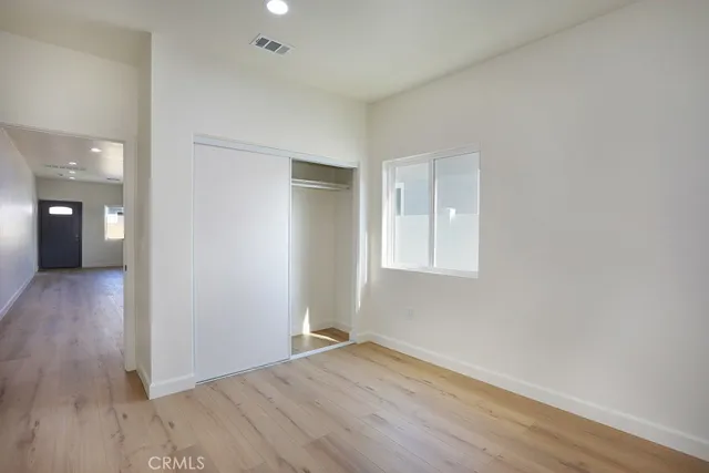 an empty room with wooden floor closet and windows