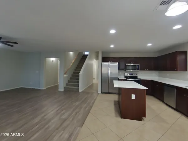 a view of an empty room with a kitchen and a window