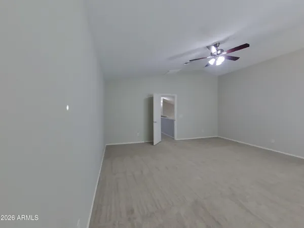 an empty room with chandelier fan and windows