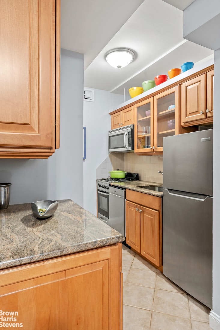 11 Riverside Drive, Unit 11AW Manhattan, NY 10023 - Photo 5 of 13 a kitchen with stainless steel appliances granite countertop a sink and a refrigerator