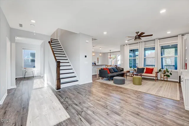 a kitchen with stainless steel appliances granite countertop a stove top oven a sink dishwasher and a refrigerator with wooden floor