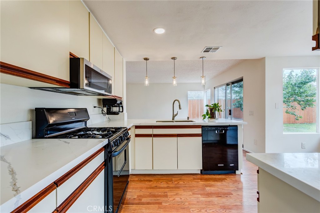 5349 Gooseberry Way Oceanside, CA 92057 - Photo 11 of 35 a kitchen with stainless steel appliances granite countertop a sink a stove and a wooden floors