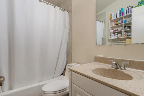 a bathroom with a granite countertop sink toilet and a mirror