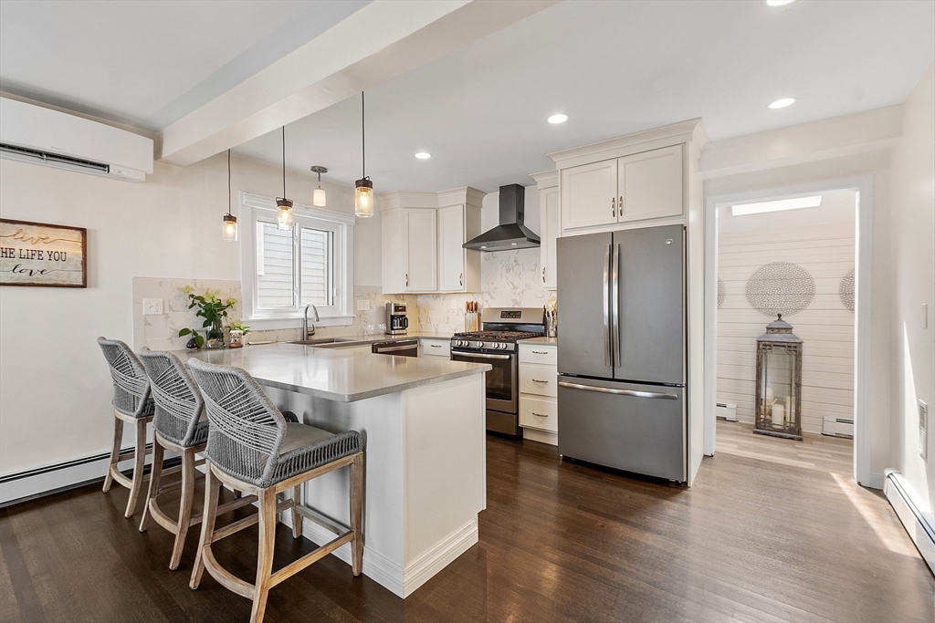 32 Maple Avenue Nahant, MA 01908 - Photo 18 of 37 a kitchen with stainless steel appliances a refrigerator a stove a sink and white cabinets with wooden floor