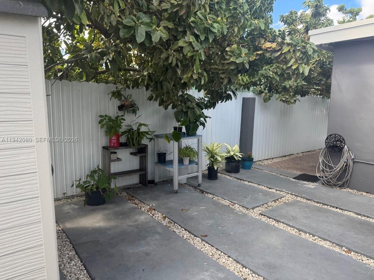 412 West 15th Street Hialeah, FL 33010 - Photo 44 of 49 a backyard of a house with potted plants and a tree