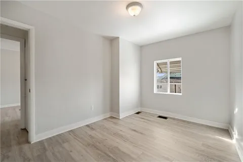 a view of an empty room with wooden floor and closet