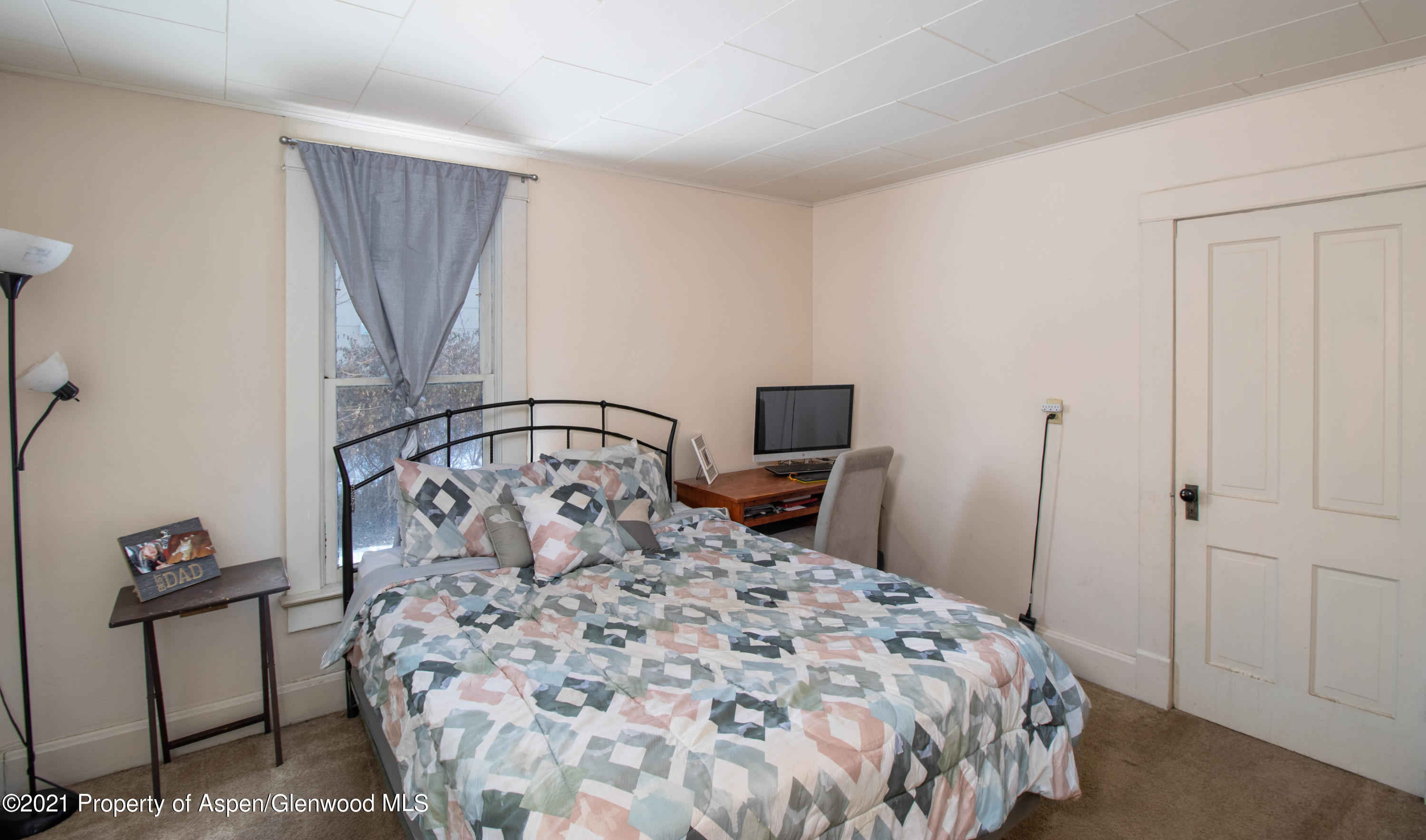 211 East 2nd Street Rifle, CO 81650 - Photo 7 of 15 a bedroom with a bed a mirror on dresser and a chandelier