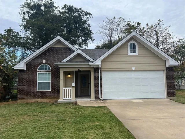 a front view of a house with a garden and yard
