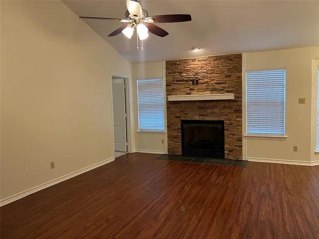 an empty room with wooden floor fireplace cabinet and a windows
