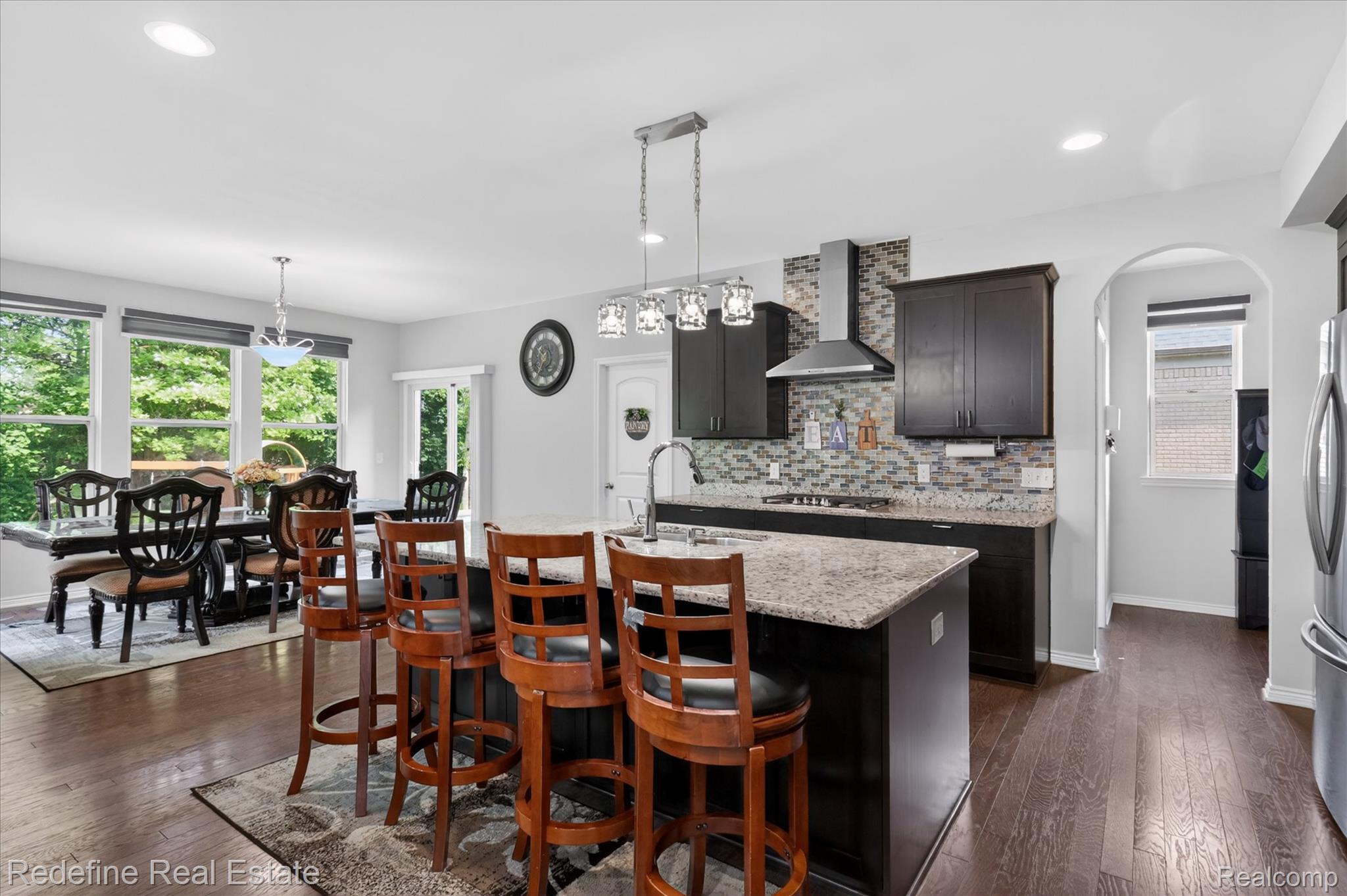 2976 Andlaur Drive Rochester, MI 48307 - Photo 14 of 60 Kitchen featuring dark cabinetry, a center island with a light-toned countertop, and a modern range hood
