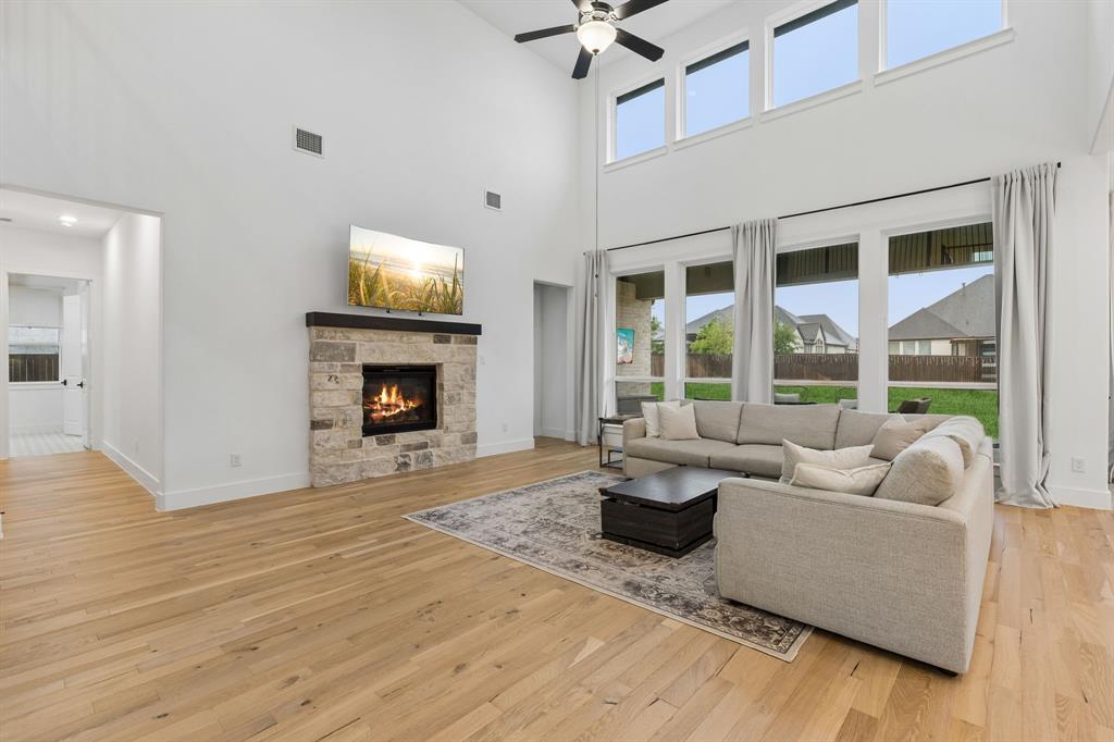 566 Broadleaf Way Haslet, TX 76052 - Photo 11 of 38 Living area featuring a floor-to-ceiling stone-clad fireplace with a dark wood mantel, high vaulted ceilings, and light wood-finish flooring