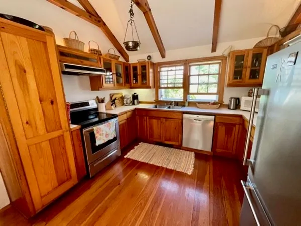 a kitchen with stainless steel appliances granite countertop wood floors and white cabinets