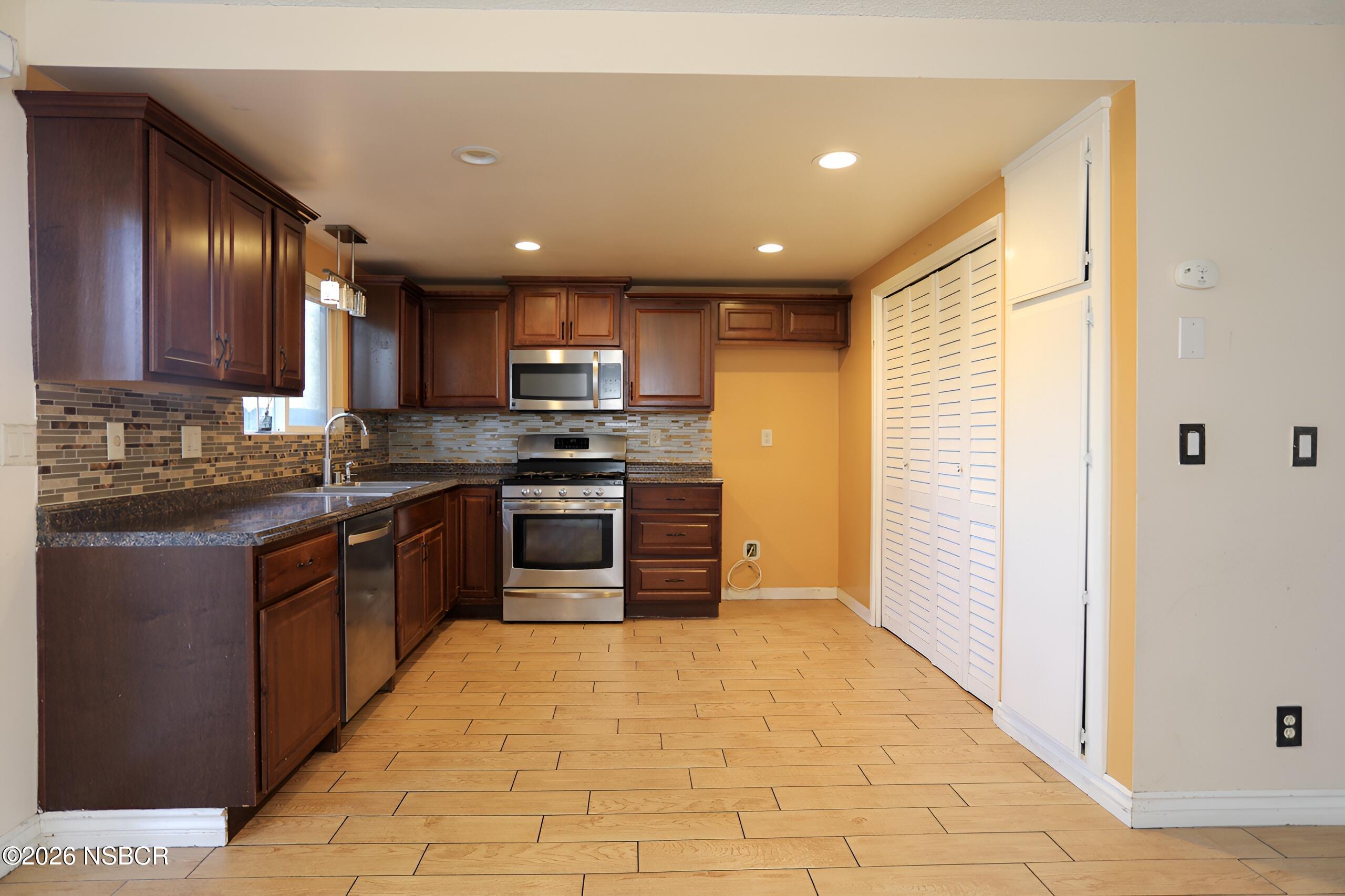 1321 North Bradley Road, Unit 14 Santa Maria, CA 93454 - Photo 4 of 30 a kitchen with stainless steel appliances granite countertop wooden cabinets a stove top oven a sink and dishwasher